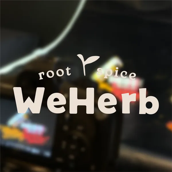 WeHerb root & spice-logoet med en lille spire, oven på et sløret foto fra packshootet